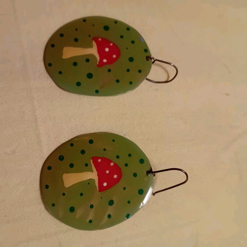 Handmade earrings with mushroom design on green background, silver clasp