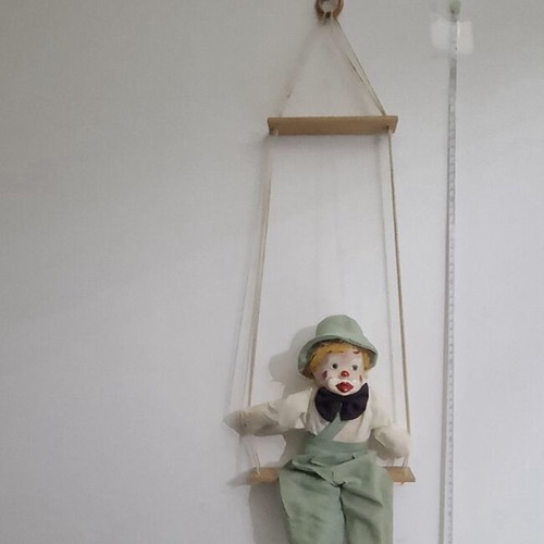 Porcelain clown doll on wooden swing, vintage collectible