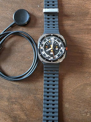 Samsung Galaxy Watch Ultra with charger and metal cases
