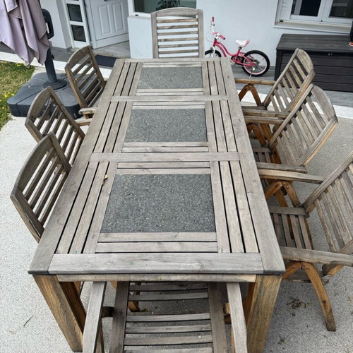 Outdoor table with 8 used teak chairs and black stone