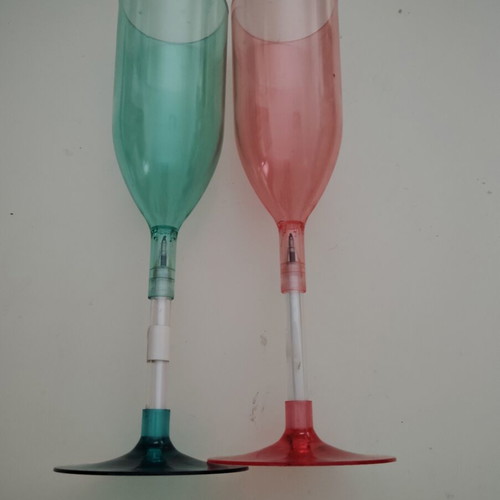 Plastic champagne glasses used, pink and green with hidden pen