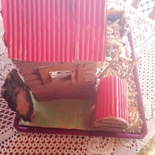Handmade decorative house with cardboard, pebbles and driftwood, new