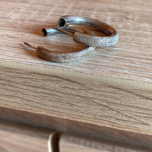 Pair of silver earrings used with textured design