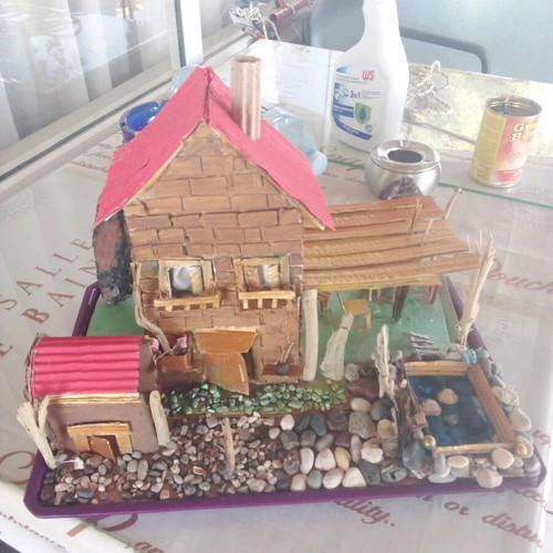 Handmade decorative house with cardboard, pebbles and driftwood, new