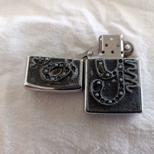 Windproof lighter with embossed metal emblem used