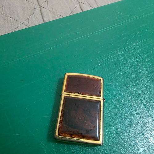 Vintage Zippo lighter in gold with glossy reddish frame