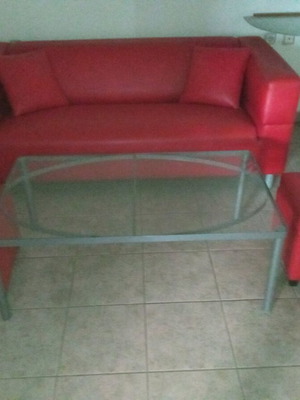 Leather two-seater sofa used red with cushions, stools and glass table