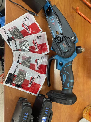 Battery-powered chainsaw with 2 batteries, charger, 5 chains, and oil bottle