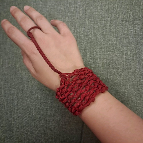 Red knitted bracelet with ring used