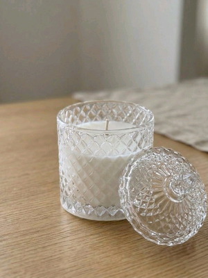 White candle in embossed glass jar with lid unused