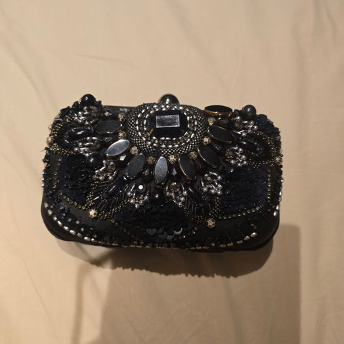 Black handheld evening bag used with small missing stone