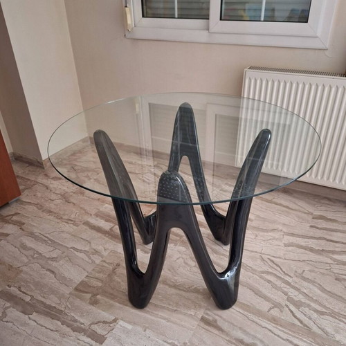 Oval dining table with tempered glass top and sculptural black base