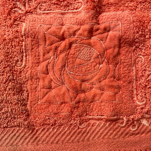 Face towel used, coral color with appliqué design