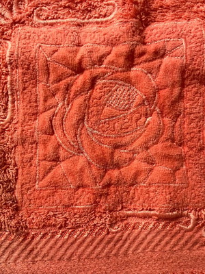 Face towel used, coral color with appliqué design