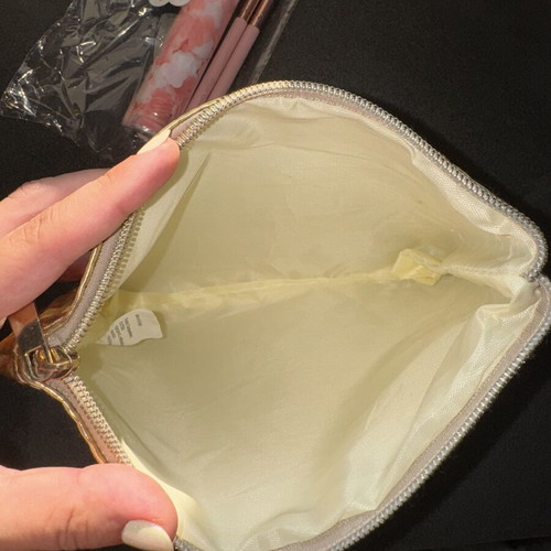 Gold makeup bag with two unused brushes