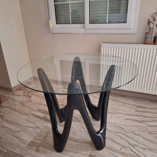 Oval dining table with tempered glass top and sculptural black base