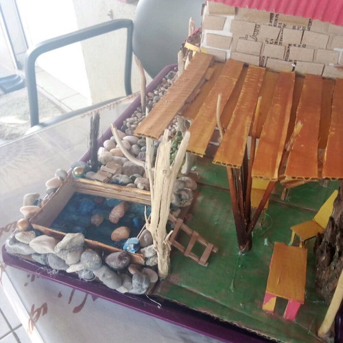 Handmade decorative house with cardboard, pebbles and driftwood, new