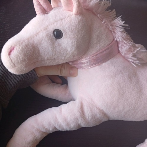 Pink plush unicorn toy used in lying position